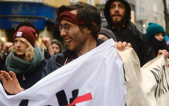 Alex hält ein Banner hoch während einer Demonstration. Er ist einer von vielen Umweltaktivist:innen in Deutschland