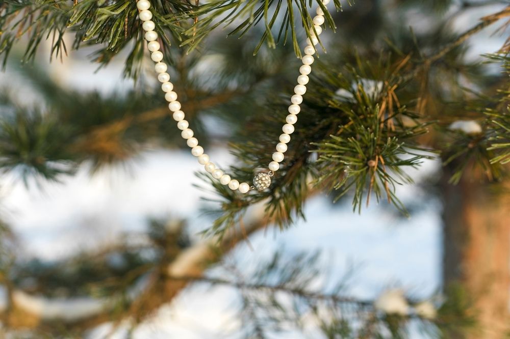Eine Halskette hängt an einem Tannenbaum. Sie ist fairer Schmuck.