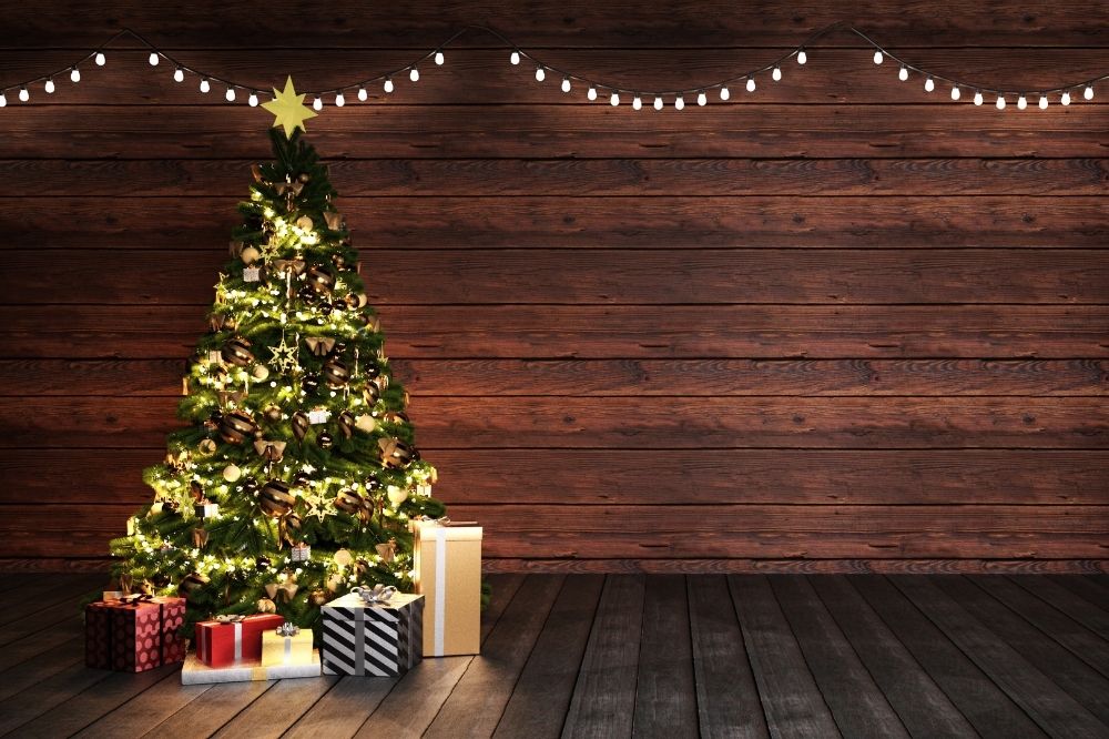 Ein geschmückter Weihnachtsbaum steht vor einer Holzwand