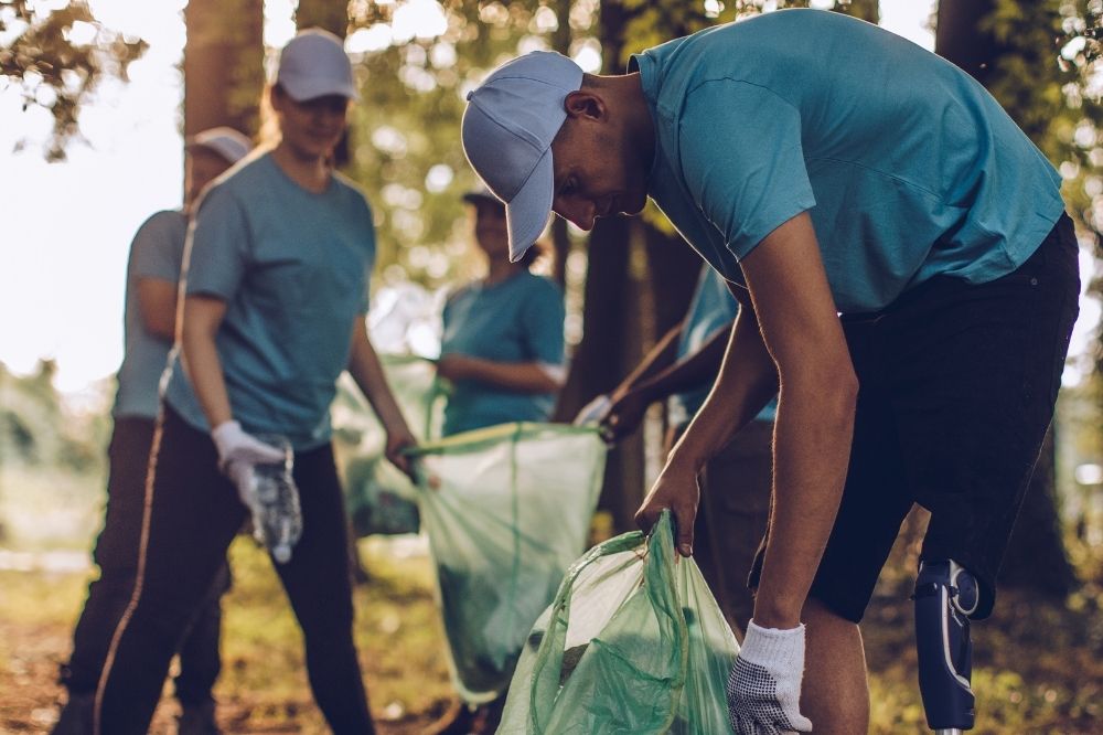 Auf dem Foto sind Menschen im Wald zu sehen. Sie sammeln dort Müll auf und packen ihn in Mülltüten. Finde alle Antworten zu Deinen Fragen zum Engagement im Naturschutz in unseren FAQ.